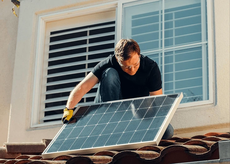 A man installing solar panels on a roof