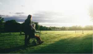 Caregiver with elderly person in wheelchair enjoying outdoor time